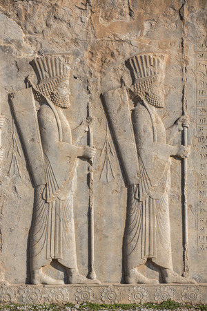 Soldiers of historical empire with weapon in hands. Stone bas-relief in ancient city Persepolis, Iran.の写真素材