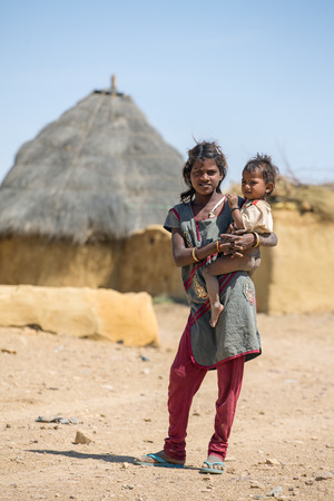 Jaisalmer, India - March 14, 2016: Unidentified tribal girl holding a baby in traditional village in Tar desert near Jaisalmer, India.のeditorial素材