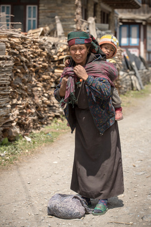 Pisang village, Nepal - May 5, 2016: Portrait of an unidentified tibetan woman with a baby in the Himalayas mountains in Lower Pisang village, Nepal. Annapurna Circuit Trekのeditorial素材