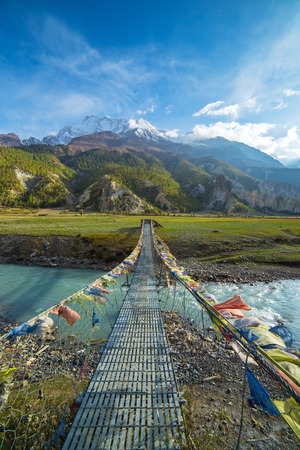 Suspension bridge with buddhist prayer flags on the Annapurna circuit trek in Nepalの写真素材