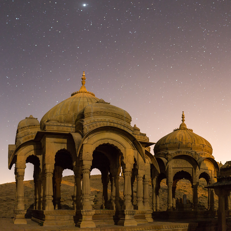 The royal cenotaphs of historic rulers, also known as Jaisalmer Chhatris, at Bada Bagh in Jaisalmer, Rajasthan, India. Night shot of ruins with starsの写真素材