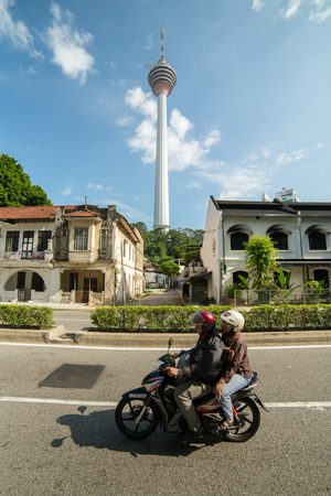 Kuala Lumpur, Malaysia - September 24, 2016: Locals drive motorbike on the street with a famous Menara KL tower at backgroundのeditorial素材