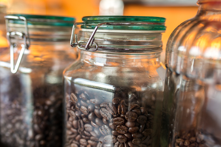 Dark roasted coffee beans in a jar of glass close-up.の写真素材