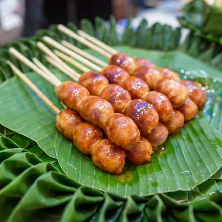Traditional Thai style grilled Sausages on the banana leaf. Isaan pork meat sausage.の写真素材