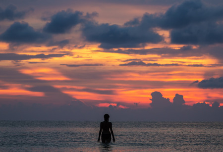 Silhouette of a girl in the tropical sea during beautiful sunset in Thailandの写真素材