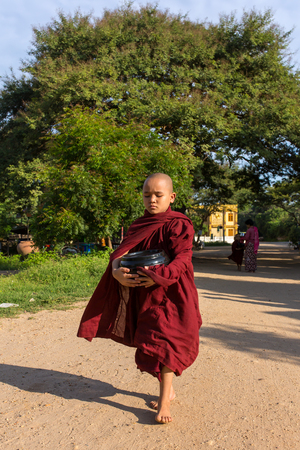 Bagan, Myanmar - October 13, 2016: Young buddhist novices walk to collect alms and offerings on the streets of Bagan, Myanmar.のeditorial素材