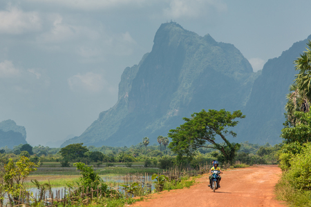 Hpa-an, Myanmar - October 19, 2016: Local burmese people riding motorbike on the country road near Hpa-an, Myanmarのeditorial素材