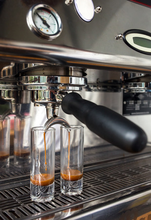 Close-up of espresso pouring from coffee machine into the two tall glasses. Professional coffee brewing conceptの写真素材