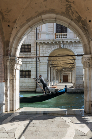 Venice, Italy - March 21, 2018: Venetian gondolier riding gondola through the side narrow canal in Venice.のeditorial素材
