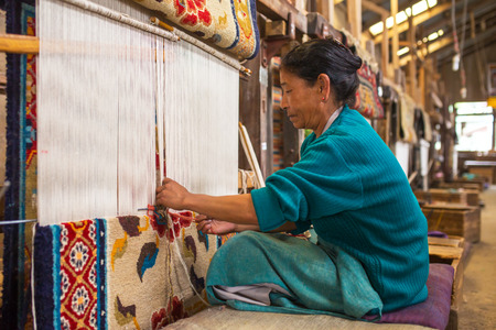 Darjeeling, India - April 19, 2017: Unidentified tibetan woman works as weaver in the carpet workshop of Tibetan Refugee Self Help Center, Darjeeling, Indiaのeditorial素材