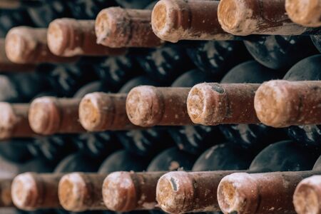 Wine bottles stacked up in old wine cellar close-up backgroundの写真素材