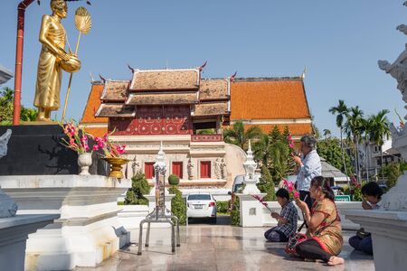 Thai people praying in front of Wat Phra Singh temple in Chiang Mai, Thailand.のeditorial素材