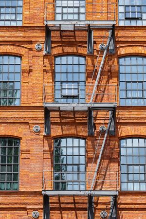 Red brick classic industrial building facade with fire escape ladder stairs. Loft construction facade conceptの写真素材