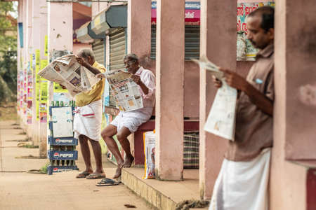 Unidentified indian men reading newspapers outside in Kerala , Southern Indiaのeditorial素材
