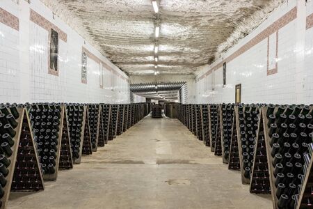 Sparkling wine bottles stacked up in old wine cellar close-up background.の写真素材