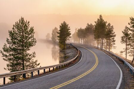 Finnish landscape with narrow car road through the lake.の写真素材