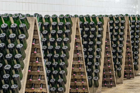 Sparkling wine bottles stacked up in old wine cellar close-up background.