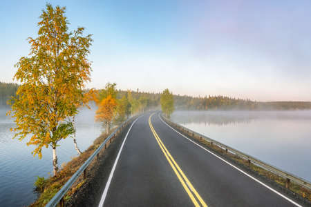 Finnish landscape with narrow car road through the lake.の写真素材