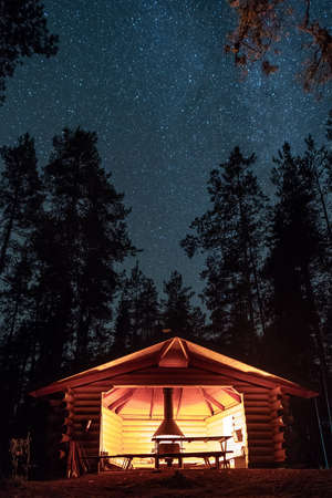Wooden shelter and fireplace with starry night sky at background in Finland.の写真素材