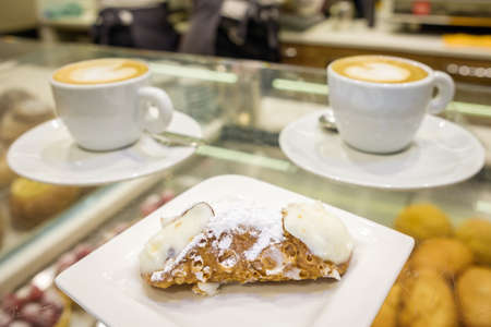 Two cups of cappuccino and fresh ricotta cannoli dessert close-up in coffee bar in Sicily, Italy.の写真素材