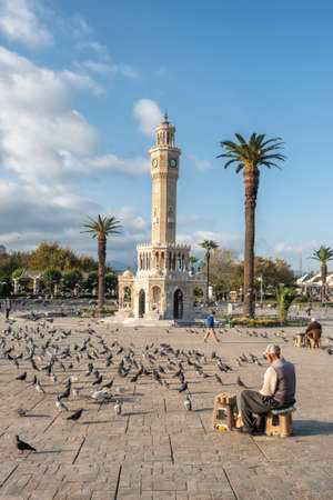 Unidentified turkish senior man selling food for pigeons near the Clock Tower of Izmir at Konak Square in Turkeyのeditorial素材