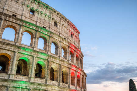 The famous Colosseum in Rome illuminated in Italian flag tricolore at twilightの写真素材