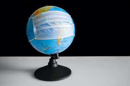 Earth globe in sterile medical mask at the tableの写真素材