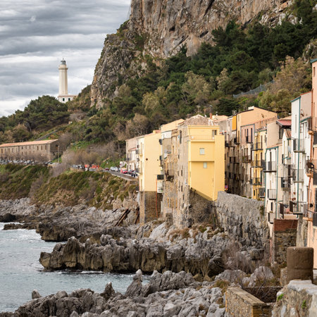 Old stone houses and lighthouse on the rocky coast of Cefalu town in Palermo region, Sicily, Italy.の写真素材