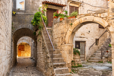 Picturesque street in Trogir city with flower pots and fresh laundryの写真素材