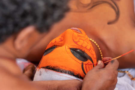 Hindu priest do make up for Theyyam performer during temple festival
