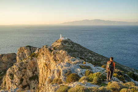 Unidentified man hiking on the cliff at Datca peninsula with Knidos lighthouse at sunset in Turkey.のeditorial素材