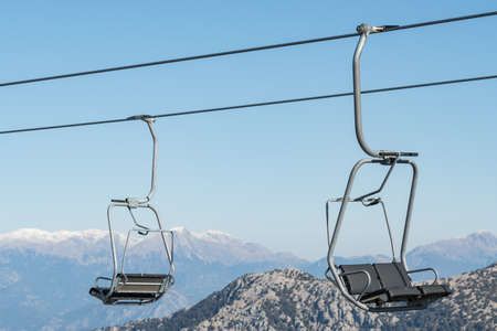 Cable car seats close-up with snow mountains at background.の写真素材