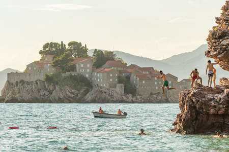 Cliff Jumping into the sea with famous Sveti Stefan island at background in Montenegro.のeditorial素材