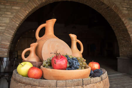 Serving barrel with clay jugs and fruits at the winery in Georgiaの写真素材