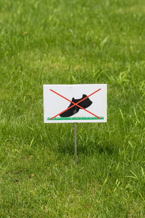 Do not walk on the grass sign placed on a beautiful green lawn.の写真素材