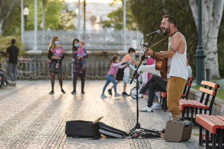Street musician playing guitar and singing songs in Tavira town, Portugal