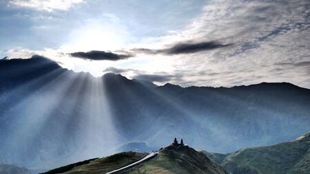 Monastery in Kazbegi Geogrian Mountains with lights beam and cloudy sky