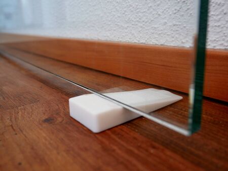 Door white plastic stopper sticked into glass doorの写真素材