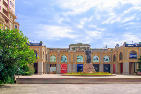 Baku, Azerbaijan. Bronze monument on a marble pedestal to the great Azerbaijani poet Nasimi, against the background of the shopping center, the house of oil workers and the blue sky.の写真素材