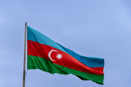 Baku, Azerbaijan. Azerbaijan Flag Waving in Clear, Blue Sky. It's a horizontal tricolor of blue, red, and green, with a white crescent and an eight-pointed star centered on the red stripe.の写真素材