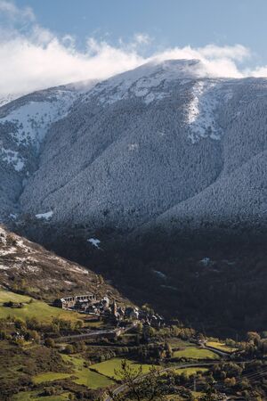 Vertical photo of a snowy mountains next to a valley with a village