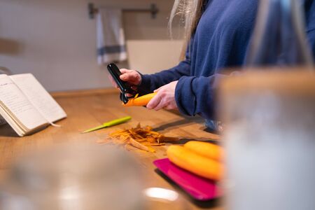 Detailed drawing of a woman's hands peeling carrots in the kitchen with her cookbook and other carrots on a precision scaleの写真素材