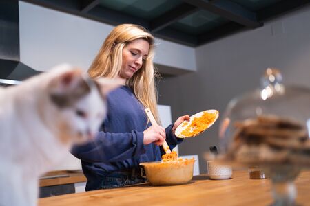 Young girl concentrating on mixing carrots with eggs and sugar in the kitchen with a close-up of a...