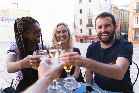 Friends drinking drinks on the terrace of a bar. The camera toasts with his friends happily. New normality conceptの写真素材