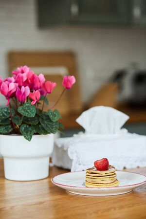 A plate with pancakes and a flower pot in the kitchenの写真素材