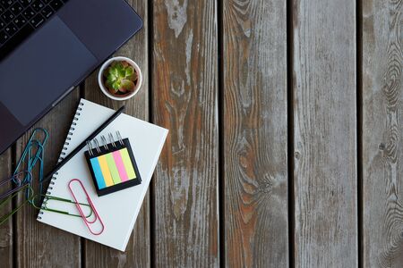 Workplace in office with wooden table. A flatlay with a laptop, notepad, different stationery and a...