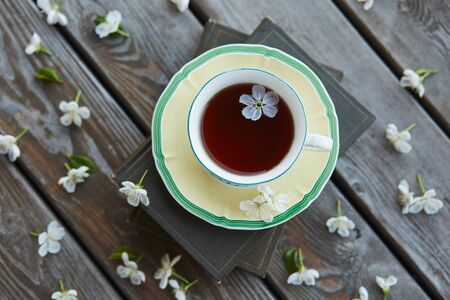 A cup of tea on a pile of books covered with cherry flowers.の写真素材