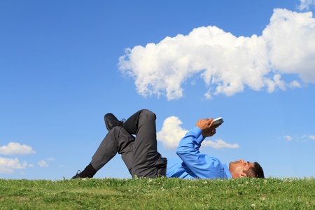 businessman laying down on the grass and working with tablet の写真素材