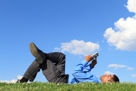 businessman laying down on the grass and working with tablet の写真素材