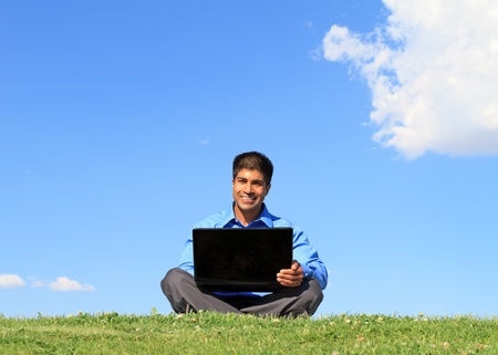 happy businessman with laptop, outdoor against blue skyの写真素材